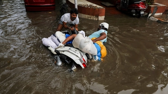 A man helps to lift a scooter of a man, as he fell at a waterlogged street in New Delhi.(REUTERS)