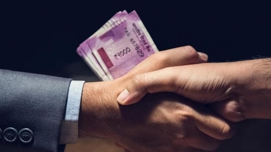 Businessmen making handshake in dark private room with money, Indian Rupee currency, in hands - bribery and corruption concept (Getty Images/iStockphoto)