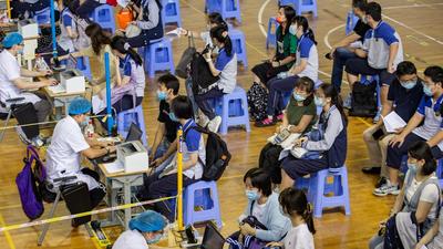 Students, accompanied by parents, wait in line to register information for vaccination against Covid-19, at a high school in Nanjing, Jiangsu province, China. (REUTERS)