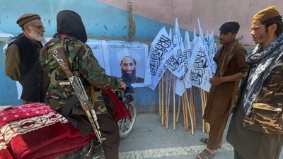 Taliban fighters look at the picture of their leader Mullah Haibatullah Akhundzada in Kabul, (Reuters File Photo)