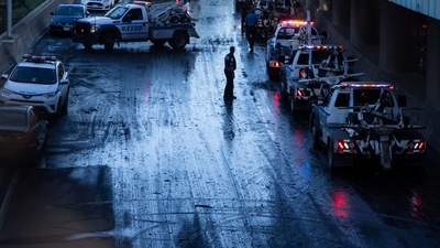 A member of the NYPD supervises tow trucks clearing cars abandoned on the Major Deegan Expressway. (REUTERS)