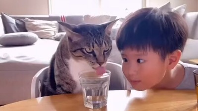 The image shows the kid looking at the cat as it drinks water. (Instagram/@rie_mrmt)