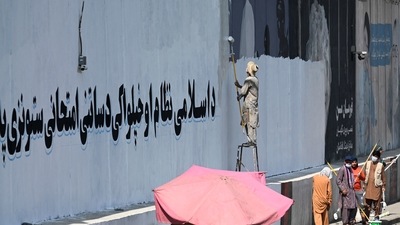A man paints over murals on a concrete wall with a message reading "For an Islamic system and independence, you have to go through tests and stay patient", in Kabul. (AFP) A man paints over murals on a concrete wall with a message reading "For an Islamic system and independence, you have to go through tests and stay patient", in Kabul. (AFP)