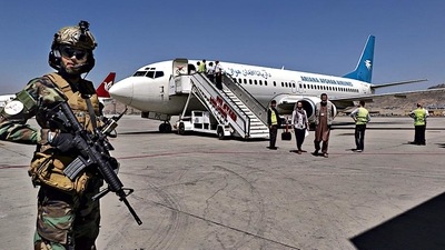 A Taliban soldier stands guard as passengers disembark at Kabul airport. (AP) A Taliban soldier stands guard as passengers disembark at Kabul airport. (AP)