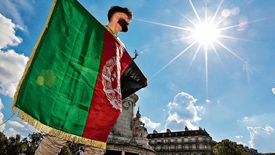 Demonstrators display Afghanistan’s national flag (left) and a placard (right) at a rally in support of the Afghan people, at the Place de la Republique in Paris on Sunday. (AFP)