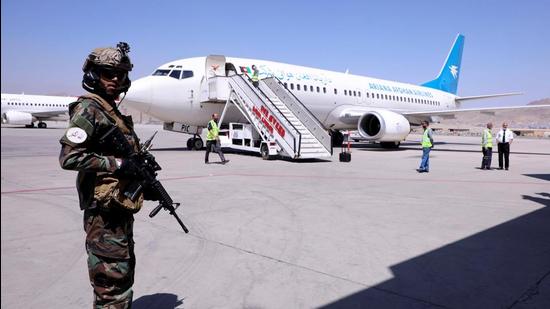 A member of Taliban forces stands guard next to a plane after its arrival from Kandahar at Hamid Karzai International Airport in Kabul, Afghanistan, on Sunday. (REUTERS)