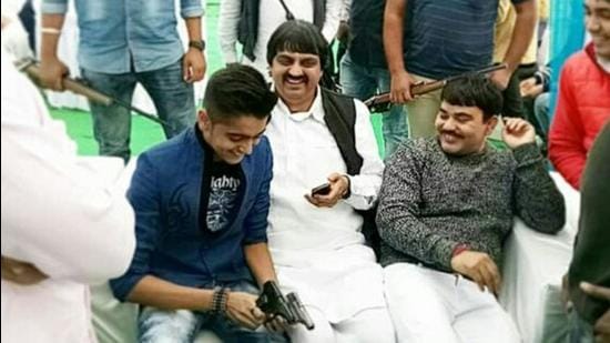 The accused, Abhishek, seen flaunting two pistols while seated next to his father. The Rohtak youth had killed his family members, including his father, mother, grandmother on August 23. His sister had succumbed to bullet wounds two days later. (HT PHOTO) The accused, Abhishek, seen flaunting two pistols while seated next to his father. The Rohtak youth had killed his family members, including his father, mother, grandmother on August 23. His sister had succumbed to bullet wounds two days later. (HT PHOTO)