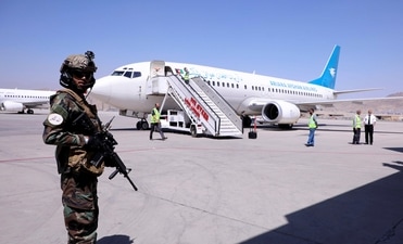 A member of Taliban forces stands guard next to a plane that has arrived from Kandahar at Hamid Karzai International Airport in Kabul, Afghanistan. (REUTERS) A member of Taliban forces stands guard next to a plane that has arrived from Kandahar at Hamid Karzai International Airport in Kabul, Afghanistan. (REUTERS)