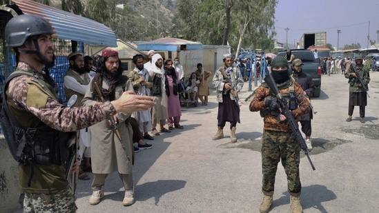 A Pakistani paramilitary soldier, left, and Taliban fighters stand guard on their respective sides, at a border crossing point between Pakistan and Afghanistan, in Torkham, in Khyber district, Pakistan.&nbsp;(AP Photo)