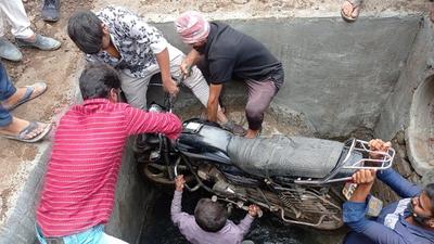 Residents of Prabhat nagar in Pune remove the bike of Ramesh Koli, the man who fell into the uncovered manhole and suffer injuries, on Monday. (HT) Residents of Prabhat nagar in Pune remove the bike of Ramesh Koli, the man who fell into the uncovered manhole and suffer injuries, on Monday. (HT)