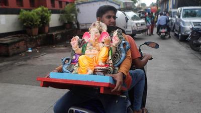 A devotee carries an idol of Ganesh, the deity of prosperity, on a scooter, on the eve of the Ganesh Chaturthi festival. (REUTERS)