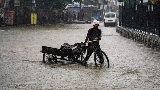 A tri-kart puller drags his rickshaw through a waterlogged road following heavy rainfall at Mahipalpur, in New Delhi on September 11. (ANI)