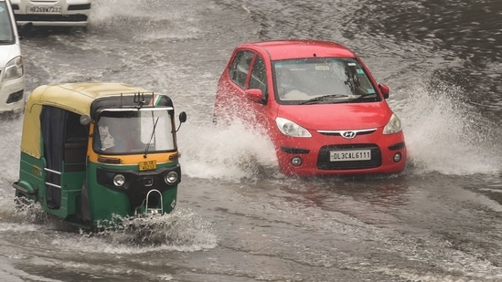 Commuters wade through a waterlogged area following heavy rains in New Delhi on September 11.(PTI)