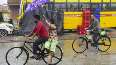 Commuters make their way through rain in Punjab’s Amritsar where mercury dropped nine notches below normal. (Sameer Sehgal /HT)