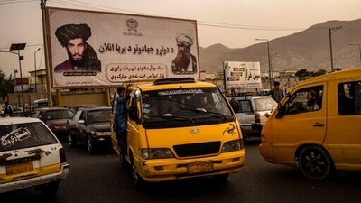 Vehicles drive past a mural paying homage to late Taliban founder Mullah Mohammad Omar, left, and the late founder of the feared Haqqani network, Jalaluddin Haqqani, in Kabul. (AP)