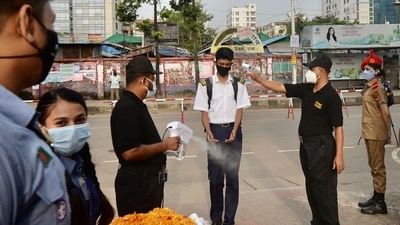 An official checks the body temperature of a student upon his arrival at the Rajuk Uttara Model College in Dhaka on September 12, as Bangladesh schools reopened after 18 months in one of the world's longest shutdowns due to the Covid-19 coronavirus pandemic.&nbsp; (AFP)