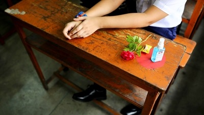 A rose and a hand sanitizer bottle are placed next to a student attending a class at the Udayan Uchcha Madhyamik Bidyalaya after the government has withdrawn restrictions on educational institutions following a decrease in the number of cases of coronavirus disease (COVID-19) in Dhaka, Bangladesh. (REUTERS)