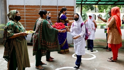 Teachers welcome students with roses at the Udayan Uchcha Madhyamik Bidyalaya as schools reopen after 18 months in Bangladesh. (REUTERS)
