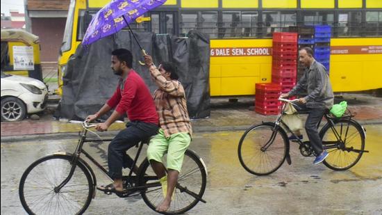 Commuters make their way through rain in Punjab’s Amritsar where mercury dropped nine notches below normal. (Sameer Sehgal /HT)