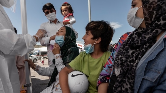 Afghan refugees who escaped Herat shortly after the Taliban takeover the city, being administered a coronavirus swab test at the Italian Red Cross camp. (Fabio Bucciarelli for The New York Times)