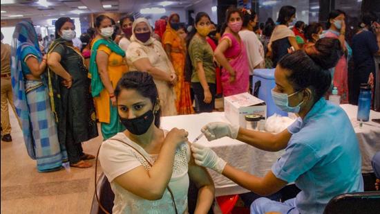 A health worker administers a dose of Covid-19 vaccine to a beneficiary, at a district hospital in Noida, on Monday. (PTI) A health worker administers a dose of Covid-19 vaccine to a beneficiary, at a district hospital in Noida, on Monday. (PTI)