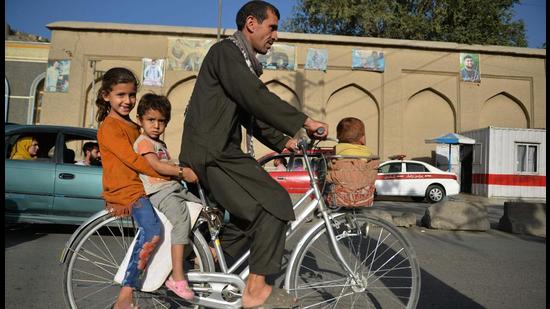 A man along with children rides a bicycle in Kabul on Monday. Reaffirming India’s long and historical ties with Afghanistan and its people, external affairs minister S Jaishankar called for humanitarian assistance providers to be accorded “unimpeded, unrestricted” access to the country”. (AFP)