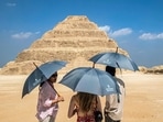 Visitors stand with umbrellas near the step pyramid of the third dynasty Ancient Egyptian Pharaoh Djoser (27th century BC) at the Saqqara Necropolis south of Egypt's capital Cairo. Visitors stand with umbrellas near the step pyramid of the third dynasty Ancient Egyptian Pharaoh Djoser (27th century BC) at the Saqqara Necropolis south of Egypt's capital Cairo.