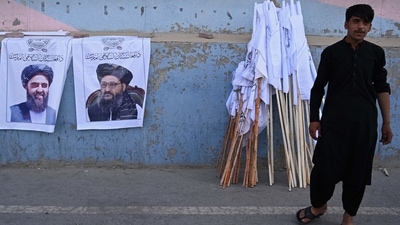 A vendor selling Taliban flags stand next to the posters of Taliban leaders Mullah Abdul Ghani Baradar and Amir Khan Muttaqi (L) as he waits for customers along a street in Kabul, following the Taliban's military takeover of Afghanistan.&nbsp; (File photo / AFP)
