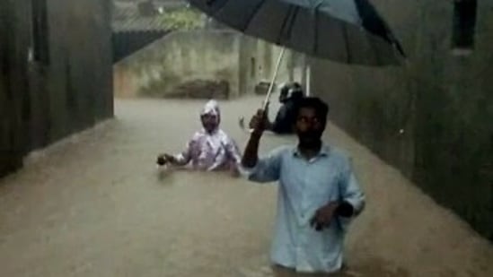 People wade through waterlogged street following heavy rainfall, in Rajkot on September 13.(ANI)