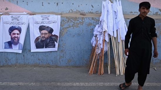 A vendor selling Taliban flags stand next to the posters of Taliban leaders Mullah Abdul Ghani Baradar and Amir Khan Muttaqi (L) as he waits for customers along a street in Kabul, following the Taliban's military takeover of Afghanistan.&nbsp;(File photo / AFP)