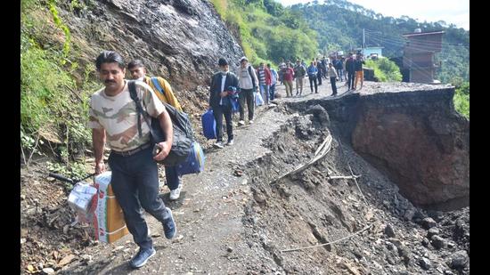 People walk past the landslide-hit stretch at Ghandal, near the National Judicial Academy at Ghannati, on the Shimla-Pathankot highway after heavy rain on Tuesday. (Deepak Sansta/HT)