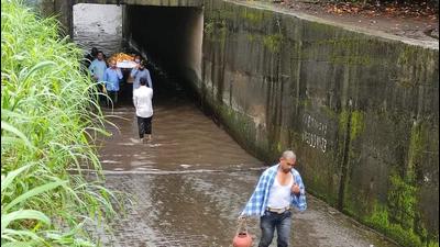 Residents carry a dead body amid water logged at the railway underpass in Badlapur. Residents carry a dead body amid water logged at the railway underpass in Badlapur.
