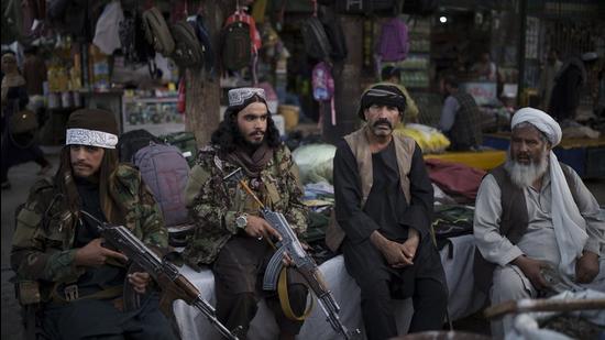 Taliban fighters sit next to street vendors at a local market in Kabul on September 10. (File photo) Taliban fighters sit next to street vendors at a local market in Kabul on September 10. (File photo)