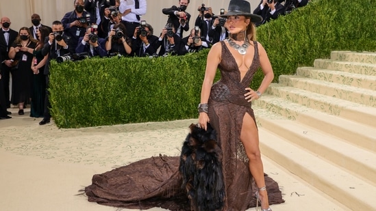 Jennifer Lopez: The actor and singer arrived at the Met Gala 2021 in a brown Ralph Lauren look that comprised a plunging gown fitted with a leather belt and feathered sleeves. Lopez accessorized the ensemble with a cowboy hat and medallion necklace.(AFP)