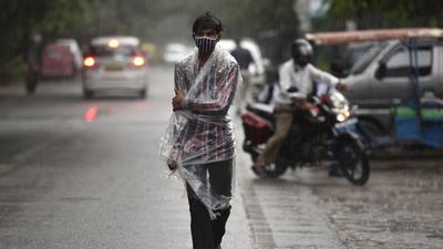 A commuter out in the rain at Sector 12, in Noida on Thursday. (Sunil Ghosh/HT Photo)