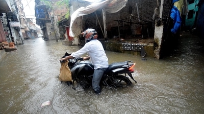A Commuter wades through a waterlogged road following heavy rainfall, in Lucknow on Thursday.&nbsp; (ANI)