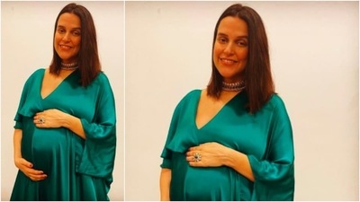 Neha Dhupia places her hand on her growing baby bump as she poses in this elegant green ensemble. (Instagram/@nehadhupia)