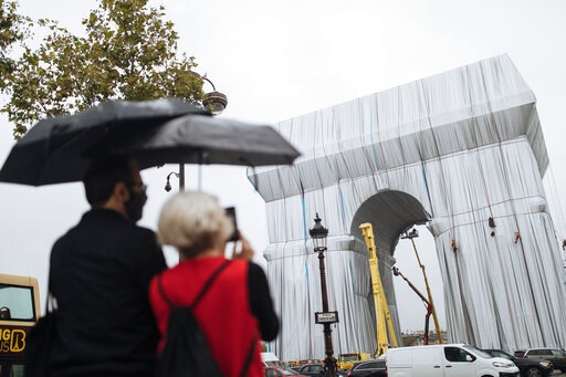 People watch workers wrapping the Arc de Triomphe monument in Paris. (AP) People watch workers wrapping the Arc de Triomphe monument in Paris. (AP)