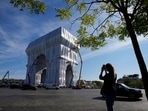 Onlooker takes a picture as workers put the final touch to wrap the Arc de Triomphe monument, in Paris. The Onlooker takes a picture as workers put the final touch to wrap the Arc de Triomphe monument, in Paris. The