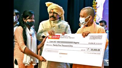 UP chief minister Yogi Adityanath hands over a cheque of Rs. 25,000 to a beneficiary during the Vishwakarma Shram Samman Yojana on the occasion of Vishwakarma Jayanti, in Lucknow on Friday. (ANI Photo)