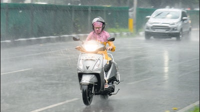 A scooterist braving the heavy showers at Madhya Marg in Chandigarh on Thursday. (Ravi Kumar/HT)