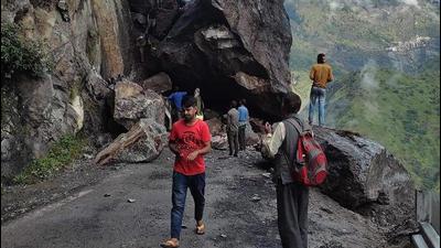 People crossing the boulders which blocked the NH-5 after a massive landslide at Chaura in Kinnaur, HP, on Friday. (HT Photo)