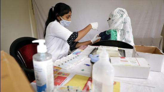 A health worker gives a Covid vaccine jab to a beneficiary at a vaccination centre in Pune. Pune district reported 803 new Covid-19 cases and eight deaths in 24 hours on Friday. (HT)