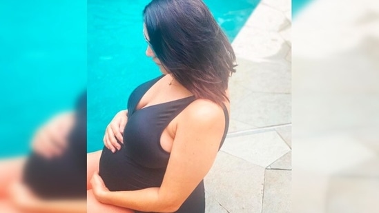 Neha Dhupia holds her baby bump as she poses in black swimwear.(Instagram/@nehadhupia)