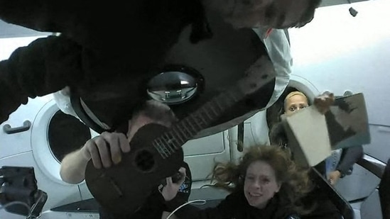 This screengrab taken from the SpaceX live webcast shows Inspiration4 crew members (from L) Jared Isaacman, Christopher Sembroski holding up a ukelele, Hayley Arceneaux and Sian Proctor holding up her artwork while in orbit. - The first space tourism mission by Elon Musk's SpaceX blasted off from Florida on September 15 and the four crew members -- a billionaire and three other Americans -- have already seen more than 25 sunsets and sunrises.&nbsp;(Handout / SPACEX / AFP)