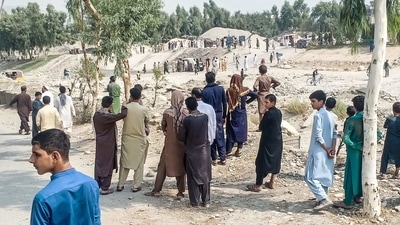 Taliban members and people gather at the site of a bomb explosion on Sunday.&nbsp; (AFP)