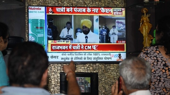 People watch the newly appointed Punjab chief minister Charanjit Singh Channi taking the oath of office. (AFP Photo) People watch the newly appointed Punjab chief minister Charanjit Singh Channi taking the oath of office. (AFP Photo)