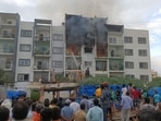 Bystanders watch firemen trying to put off the flames and bring the situation under control outside the apartment at Devarachikkana Halli area in Bengaluru. (ANI Photo).