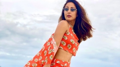 The pictures featured the actor donning an orange base draped neck crop top that came with noodle straps and sported white sunflower motifs printed all over. (Instagram/realhinakhan)