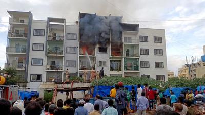 Locals gather as firefighters douse a fire that broke out at a private apartment following a gas leakage in the pipeline in Bengaluru on Tuesday. (ANI)